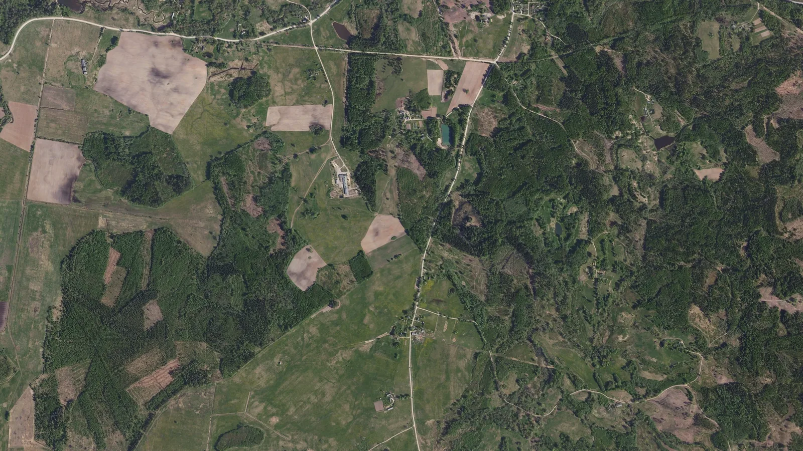 Ortofoto no augšas: meža masīvi, aramzemes lauki un pļavas Nītaures apkaimē Cēsu novadā.